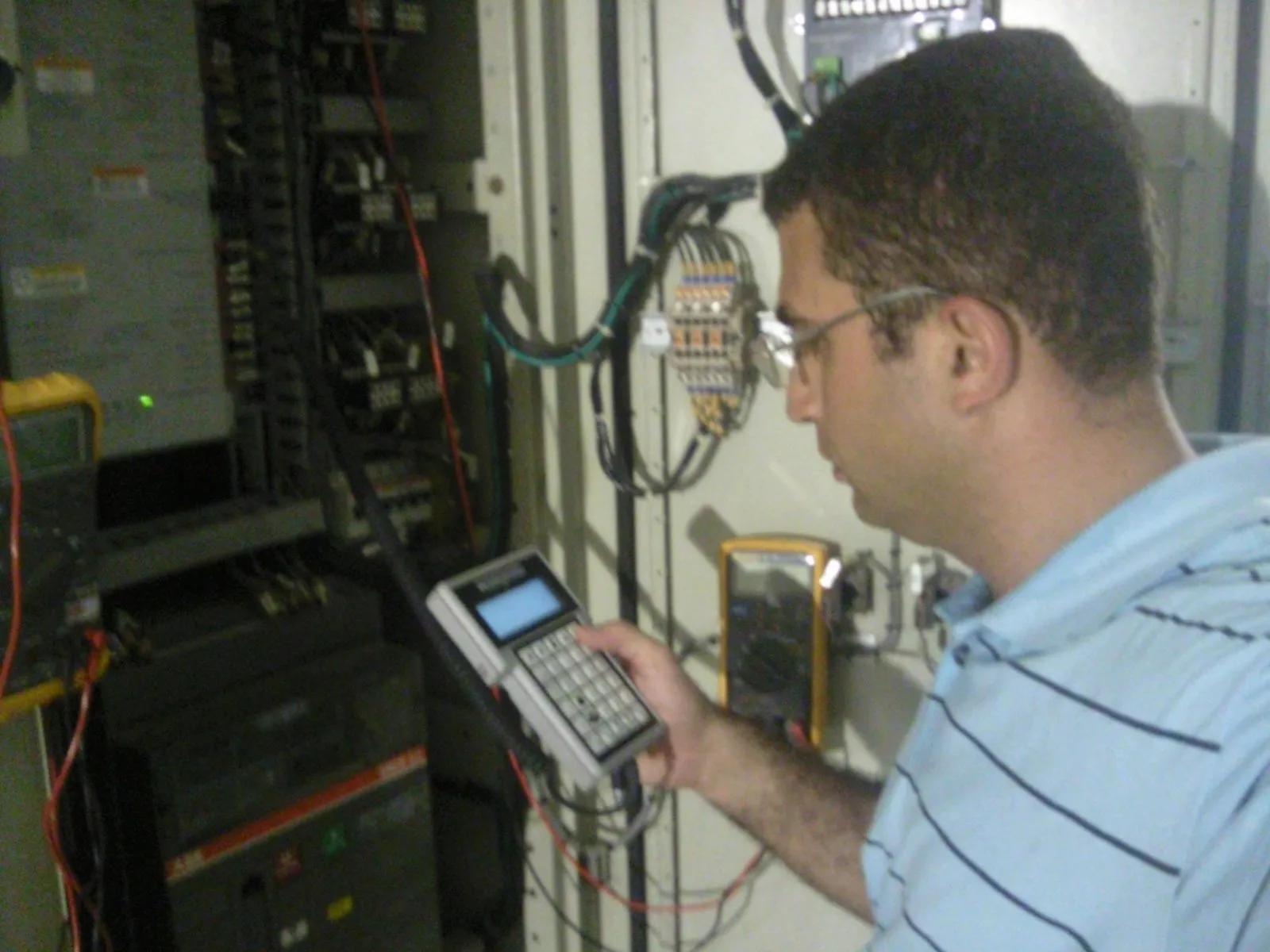 Engenheiro Márcio Zottino calibrando um controlador com programador portátil em painel industrial